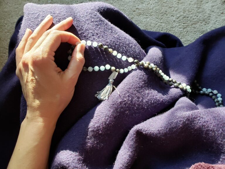 hand in jnana mudra holding a mala (prayer beads)