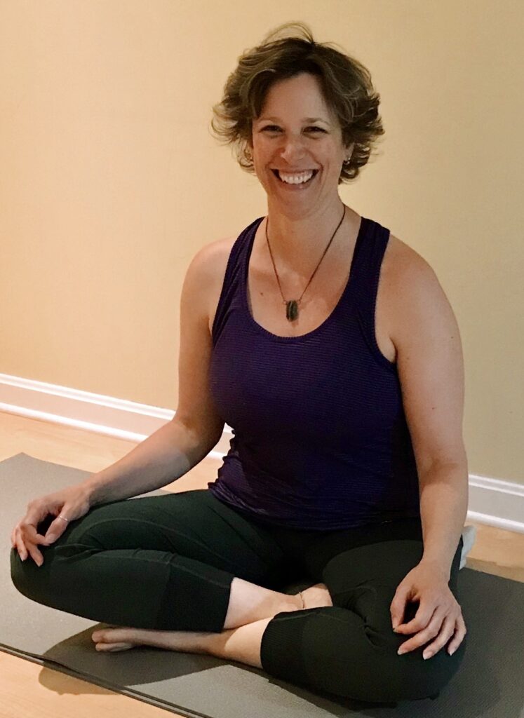 image of me sitting and smiling on my yoga mat