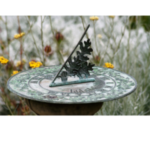 old fashioned sundial with background of yellow flowers and greenery