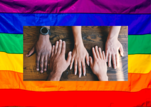 pride flag background with five human hands of varying skin color resting beside each other on a table