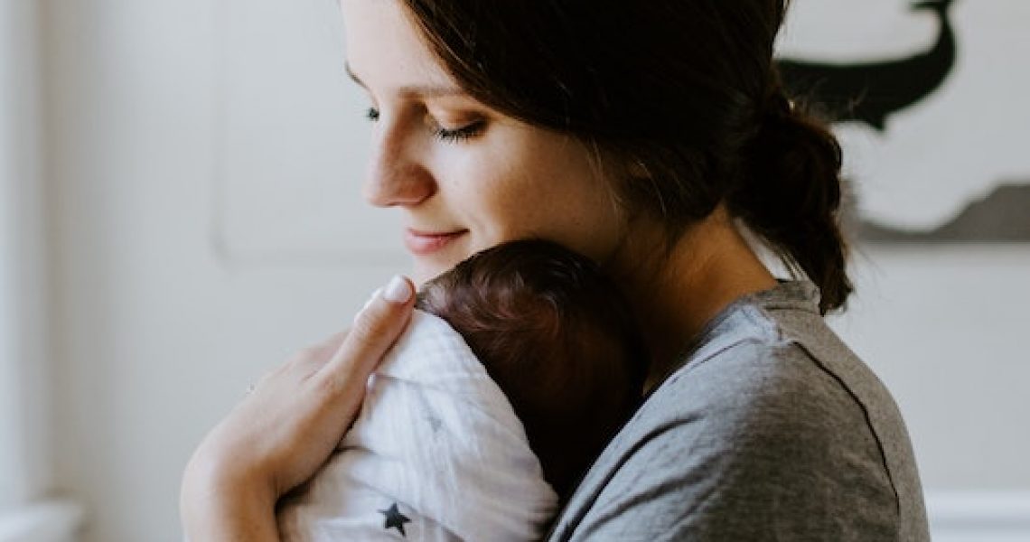 mother holding swaddled infant in nursery